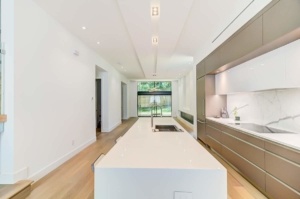 A kitchen with white counters and wooden floors.
