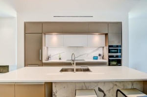 A kitchen with white counters and brown cabinets.