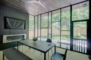 A dining room with a table and chairs, fireplace and windows.