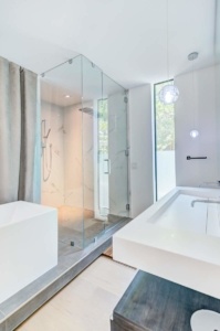 A bathroom with a large glass shower and white tub.