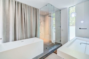 A bathroom with a large glass shower and a white tub.