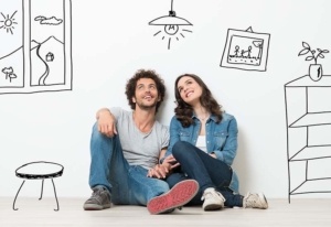 A man and woman sitting on the ground in front of wall with drawings.