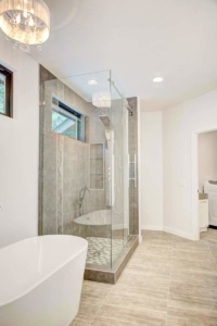 A bathroom with a large glass shower and a tub.