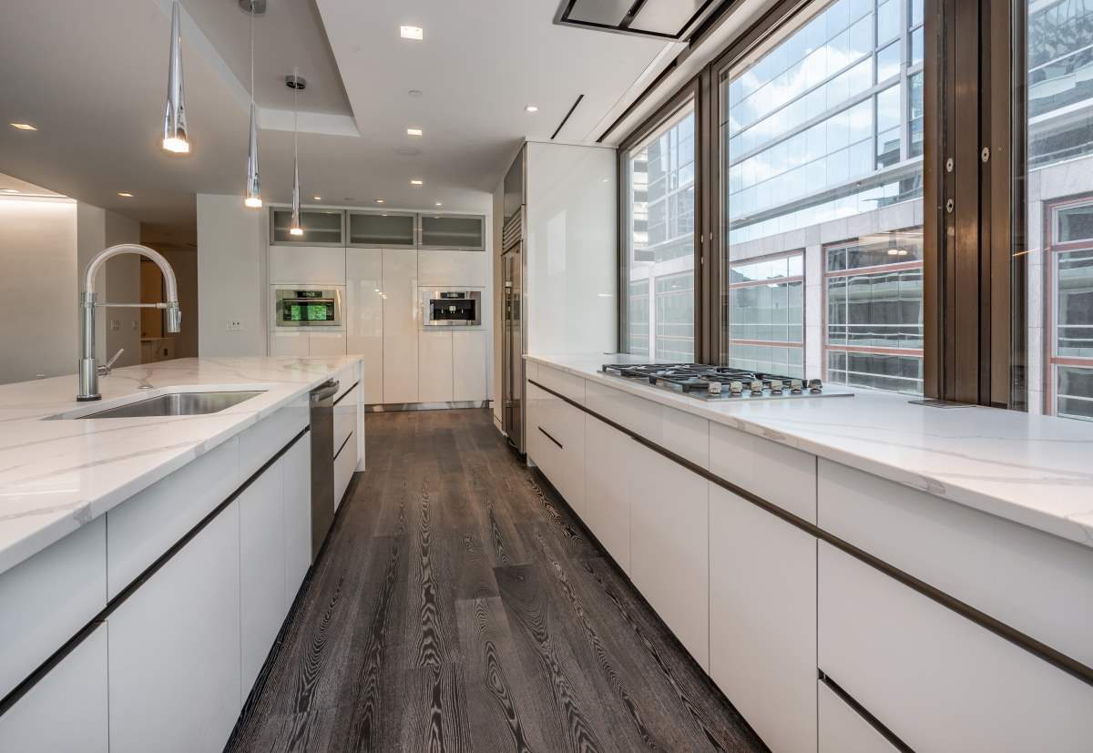 A kitchen with white cabinets and wood floors.