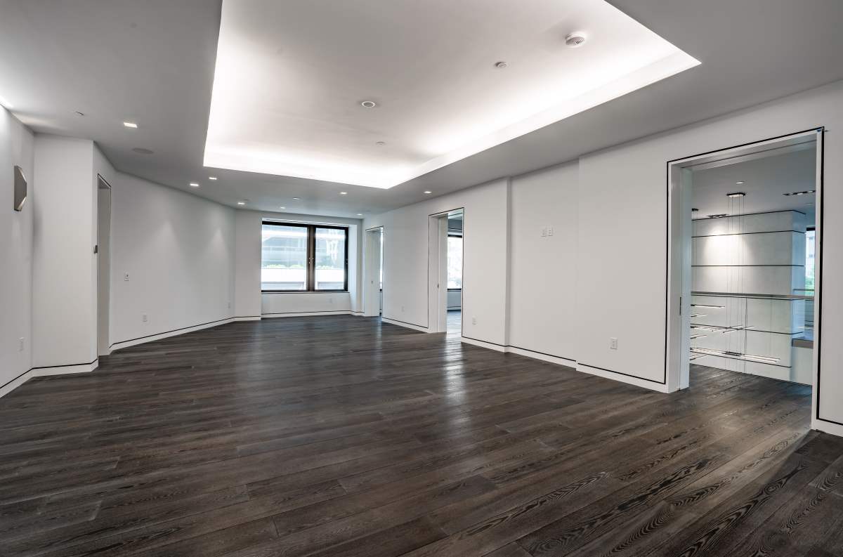 A large room with dark wood floors and white walls.