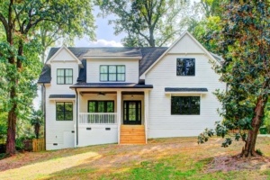 A white house with black shutters and a large porch.
