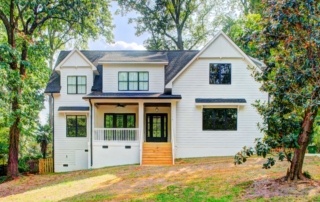 A white house with black shutters and a large porch.