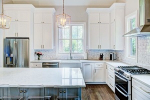 A kitchen with white cabinets and wooden floors.