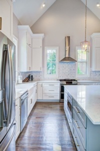 A kitchen with white cabinets and wood floors.