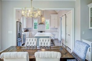 A kitchen with white cabinets and a dining room table.
