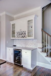 A kitchen with white cabinets and wine rack.