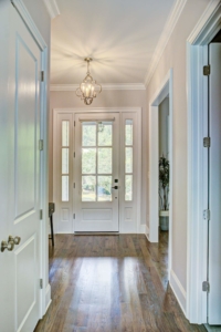 A white door leads to the hallway of a home.