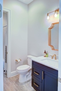 A bathroom with a toilet, sink and mirror.