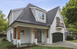 A large white house with a black garage door.