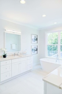 A bathroom with white cabinets and a tub.