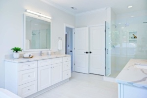 A bathroom with white cabinets and a large mirror.
