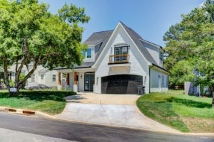 A white house with a driveway and trees in the background.