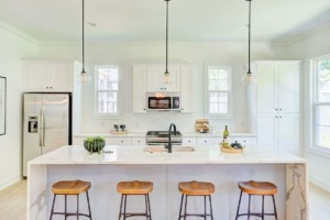 A kitchen with white counters and wooden stools.