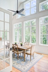 A dining room with large windows and wooden table.