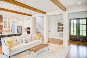 A living room with white walls and wooden beams.