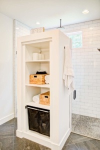 A white cabinet with baskets and towels on top of it.