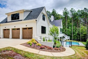 A house with two garage doors and a pool in the background.