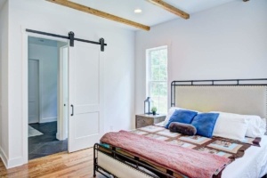 A bedroom with a bed, dresser and window.