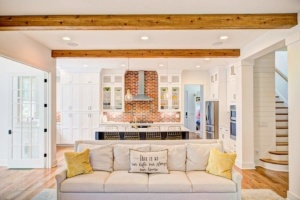 A living room with white walls and wooden beams.