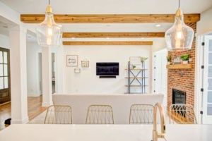 A living room with white walls and wooden beams.