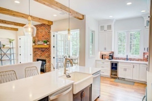A kitchen with white cabinets and wooden beams.