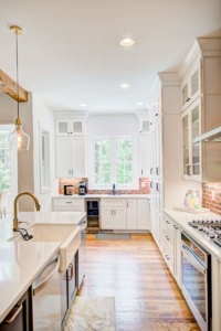 A kitchen with white cabinets and wooden floors.