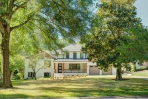 A large white house sitting in the middle of a green field.
