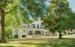 A large white house sitting in the middle of a green field.