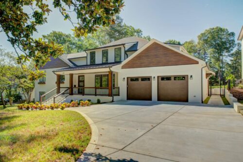 Renovated Cotswold home exterior with white brick, walnut-tone cladding and a two-car garage