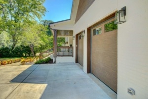 A large driveway with two garage doors and a porch.