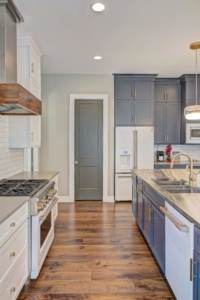 A kitchen with white cabinets and wood floors.
