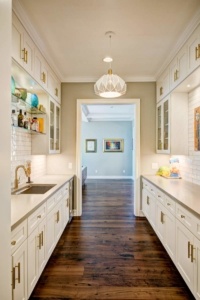 A kitchen with white cabinets and wood floors.