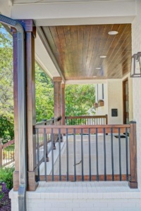 A porch with wooden floors and a metal railing.