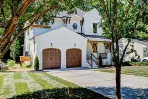 A white house with two wooden garage doors.