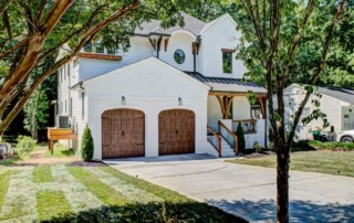 A white house with two wooden garage doors.