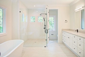 A bathroom with white cabinets and a large shower.