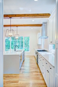 A kitchen with white cabinets and wood floors.