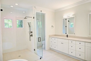 A bathroom with white cabinets and a glass shower door.