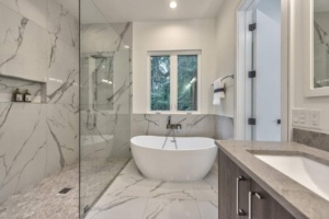A bathroom with marble walls and floors, a large tub