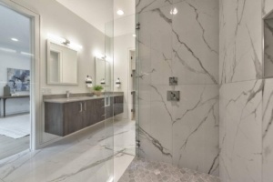 A bathroom with marble walls and floors, and a large mirror.