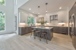 A kitchen with white cabinets and wood floors.