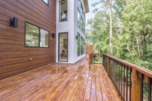 A large wooden deck with trees in the background.