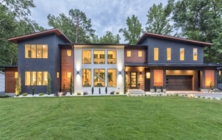 A large house with lots of windows and grass.