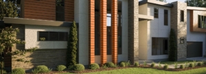 A building with three windows and bushes in front of it.