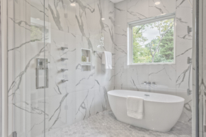 A bathroom with marble walls and floors, and a large tub.